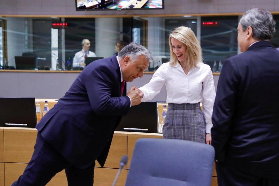 Il saluto di Orban alla premier estone Kaja Kallas. Di spalle Mario Draghi (Ansa)