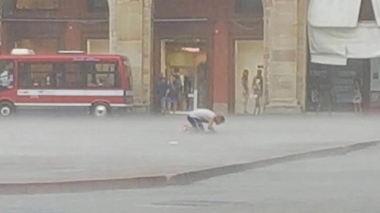 Bologna, un musulmano prega in piazza Maggiore sotto il diluvio (Foto Carlino)