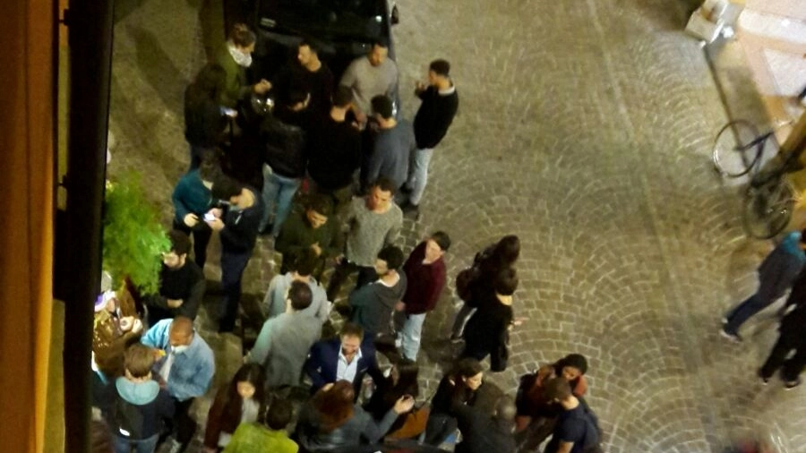 Gente in strada a tarda notte in via Petroni a Bologna