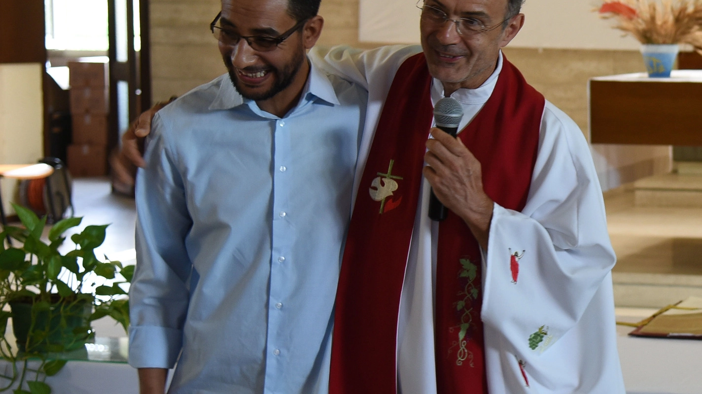 Il parroco  abbraccia El Moden Regragui, responsabile della casa della saggezza. A destra la comunità turca 