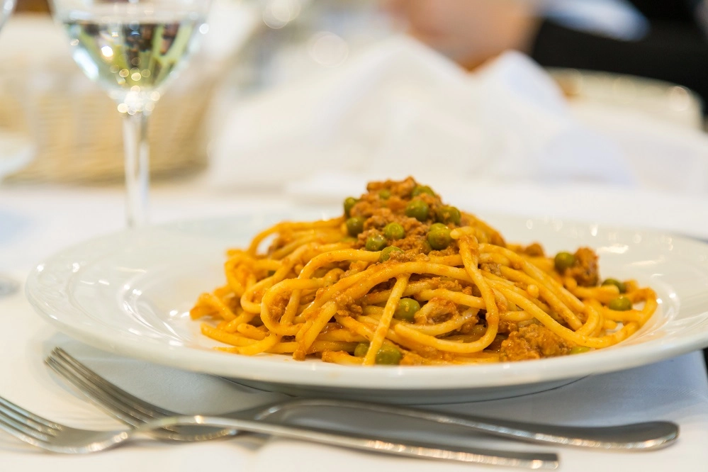 Gli spaghetti alla bolognese, con piselli e salsiccia