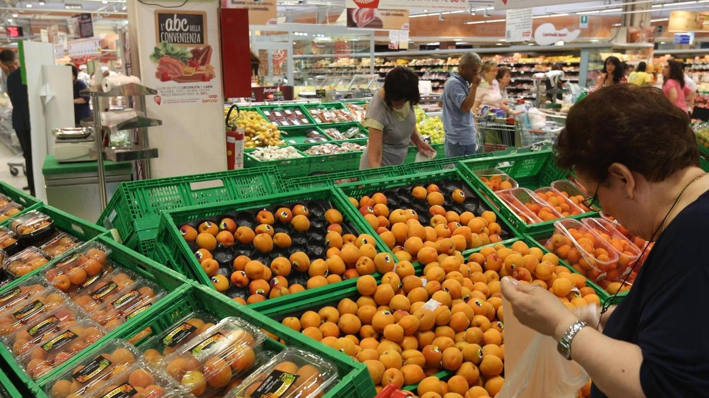 Clienti impegnati a scegliere la frutta in un reparto di supermercato
