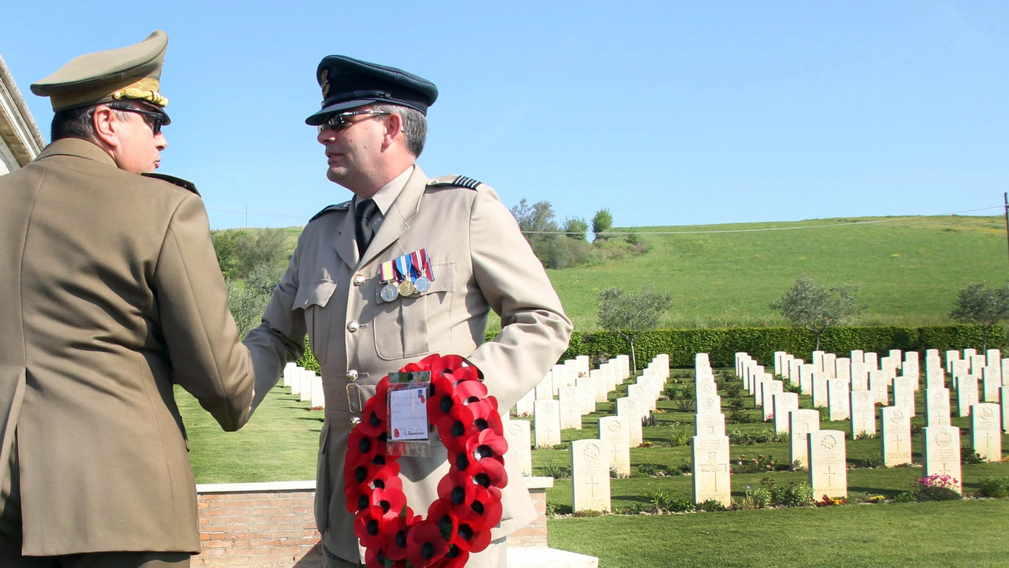 Mike Edwards, ufficiale della Royal Air Force, saluta il vice comandante del 28° al cimitero monumentale dei caduti britannici e canadesi alle porte di Montecchio