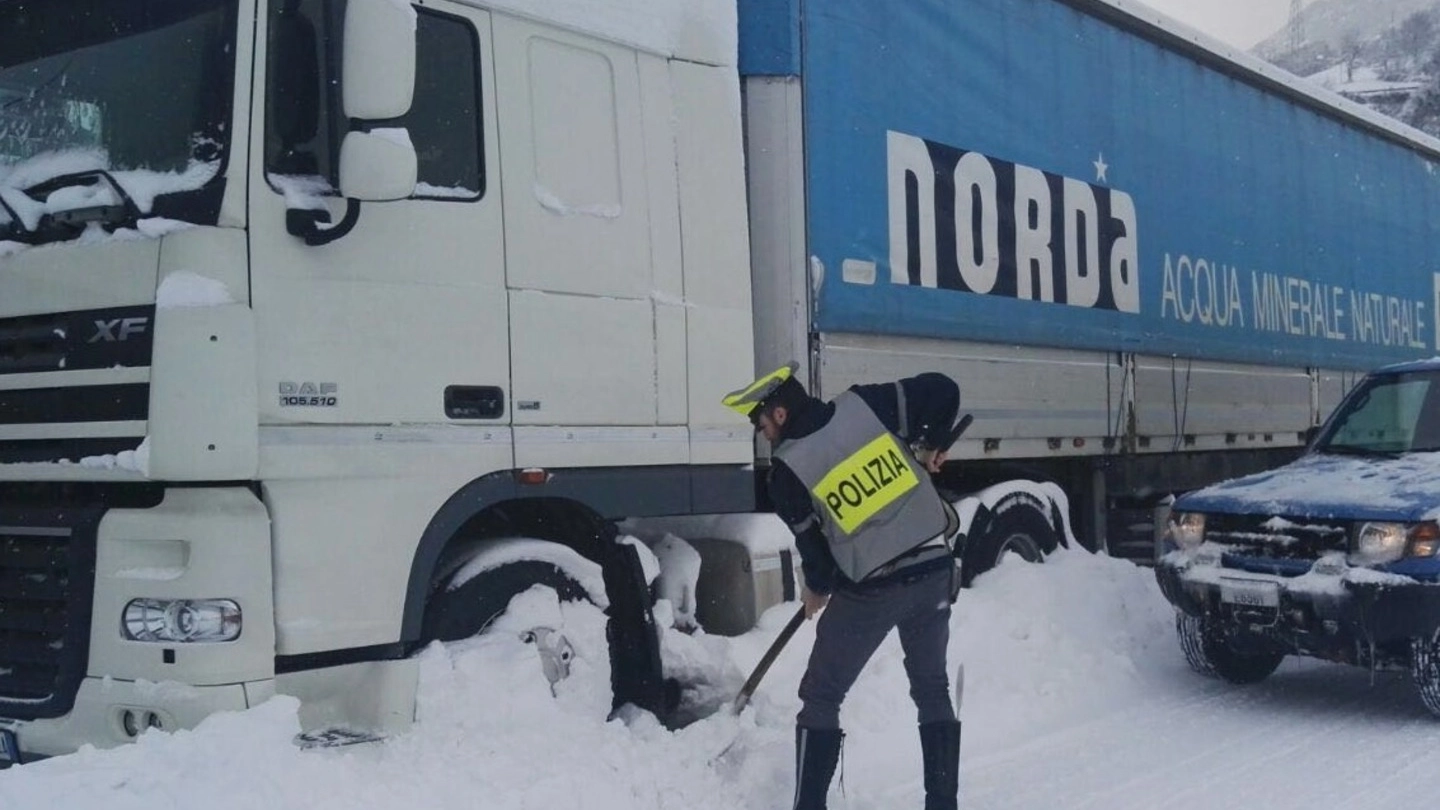 I richiedenti asilo mentre spalano la neve e un poliziotto che presta soccorso a un camionista 