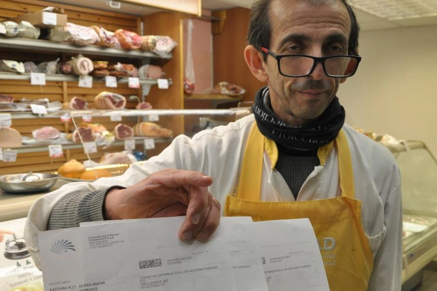 Fabrizio Golfera con le bollette in mano all’interno del suo negozio in via Lughese