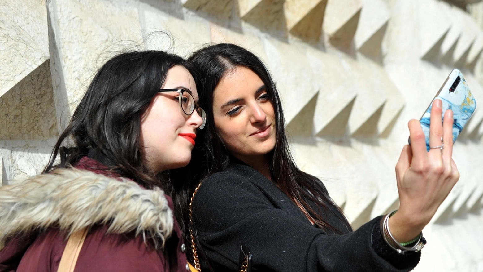 Due turiste si scattano un selfie davanti al Palazzo dei Diamanti