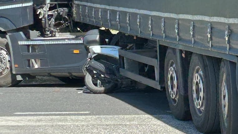 Lo scooter finisce sotto il camion:  prima dell’impatto salta e si salva