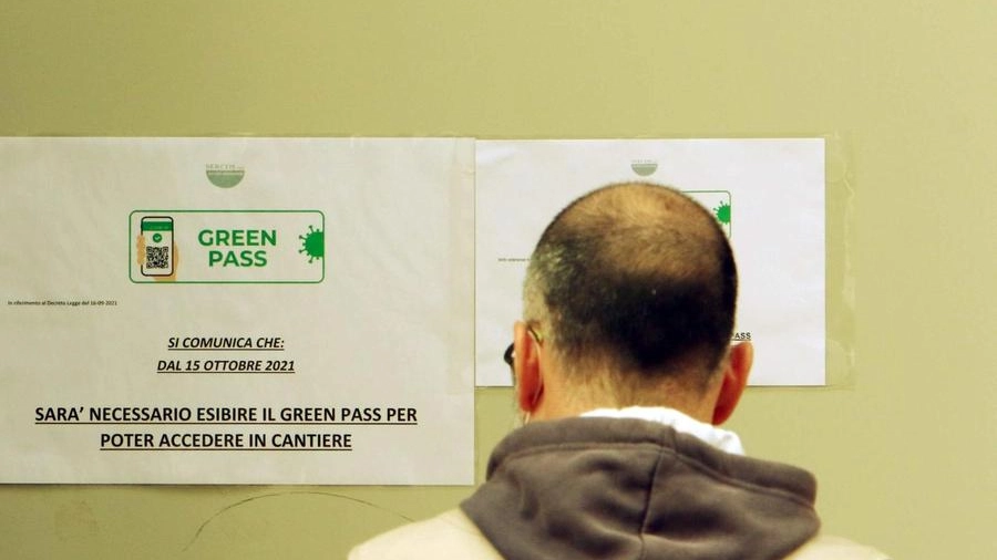 Un operaio legge il cartello in cui viene comunicato l'obbligo del Green pass (Ansa)