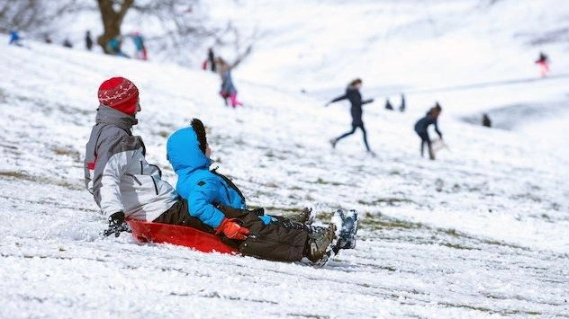 Una foto di archivio di un adulto e un bambino che scendono con lo slittino