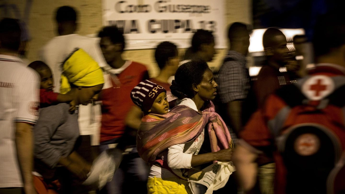 Migranti in fila per la distribuzione del cibo all’esterno del centro policulturale di Roma (foto Ansa)