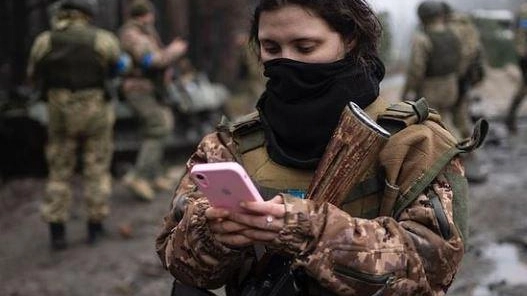 Una soldatessa ucraina scrive sul suo smartphone al fronte