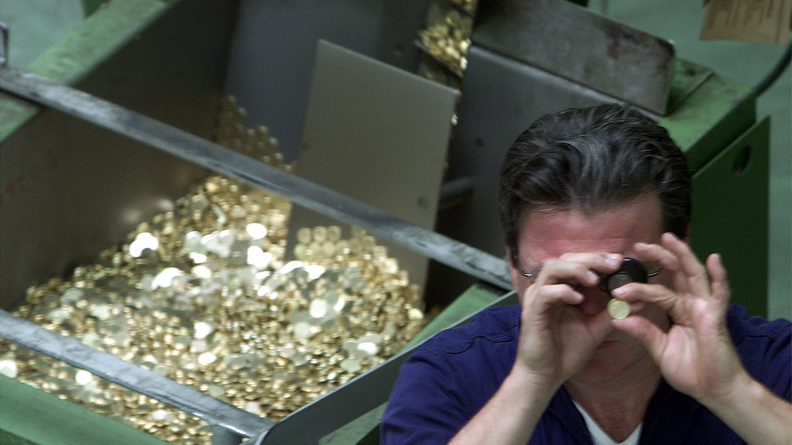 Un tecnico della Zecca esamina le monete coniate (foto Ansa)