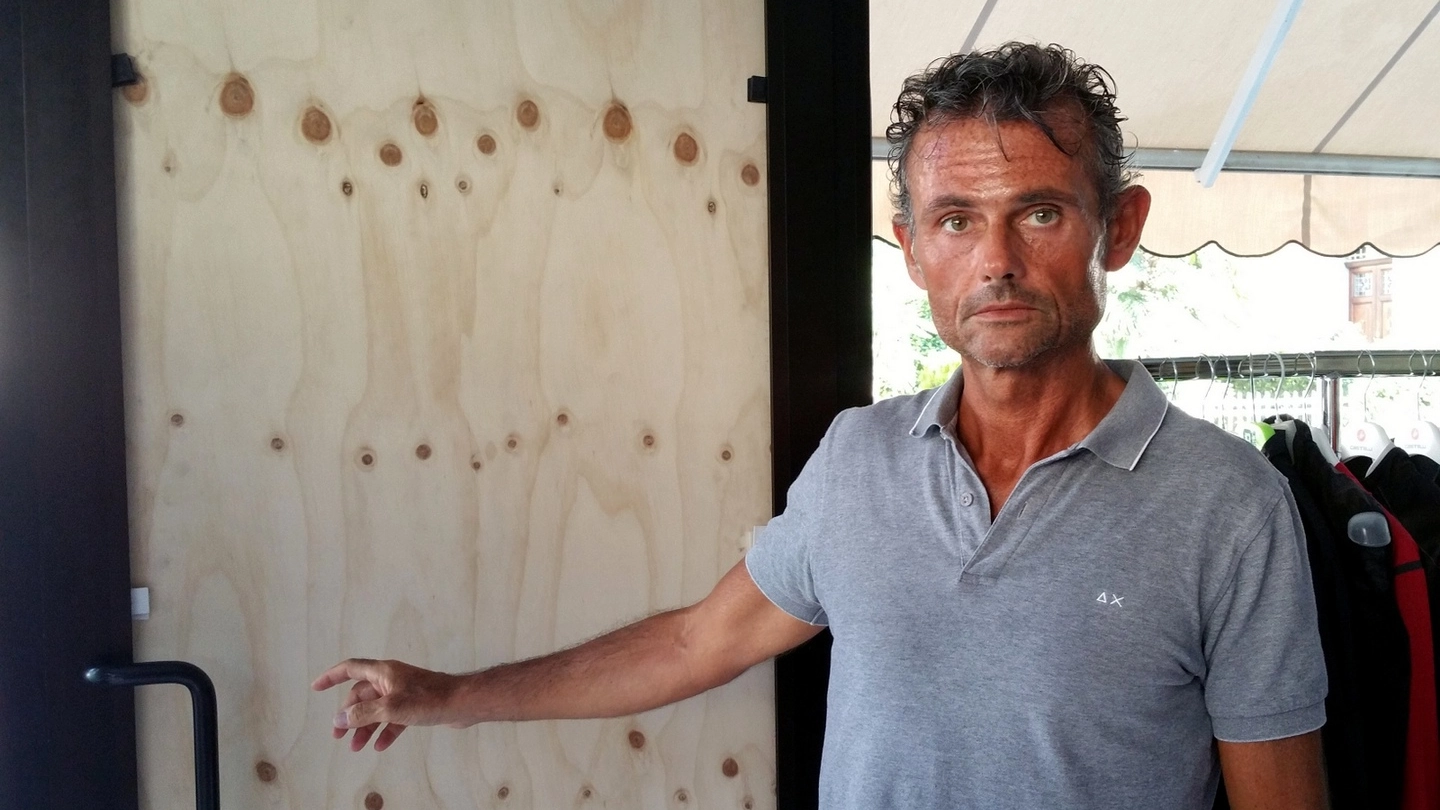 Fabio Cortini mostra la porta distrutta dai ladri e riparata, per ora, con un pannello di legno 