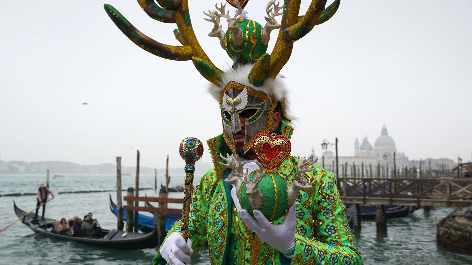 Alcuni simboli di Venezia: le gondole sulla laguna, il carnevale e sullo sfondo la basilica di San Marco