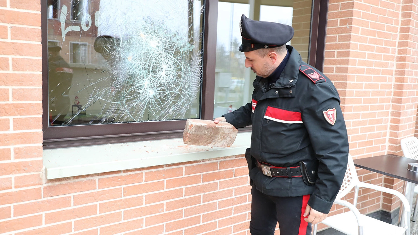 Un carabiniere mostra la pietra con cui hanno tentato di sfondare la vetrata del Fuori Porta 