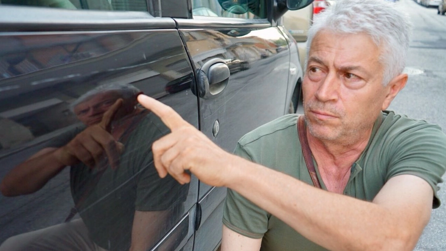 Angelo Fonti, 60 anni, titolare del Bar Stadio  di Civitanova, mostra gli sfregi sulla sua Fiat Multipla (foto De Marco)