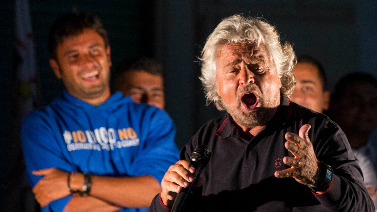 Beppe Grillo sul palco con un Alessandro Di Battista divertito