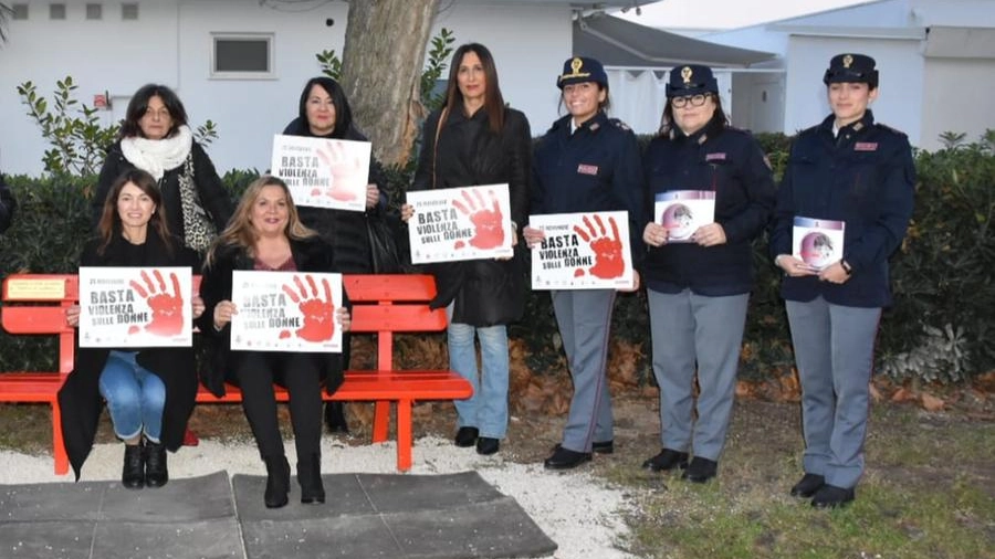 donne della politica locale e poliziotte con il cartello contro la violenza di genere
