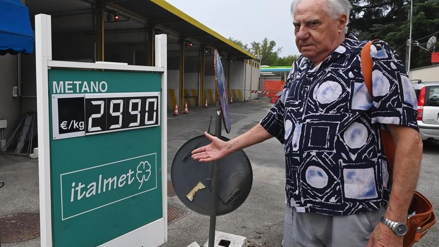 Un automobilista indica sconsolato il cartello con il prezzo del metano al chilogrammo