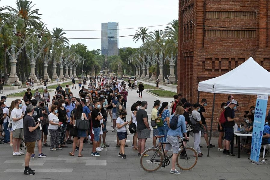 Persona in fila per essere vaccinate a Barcellona (Ansa)
