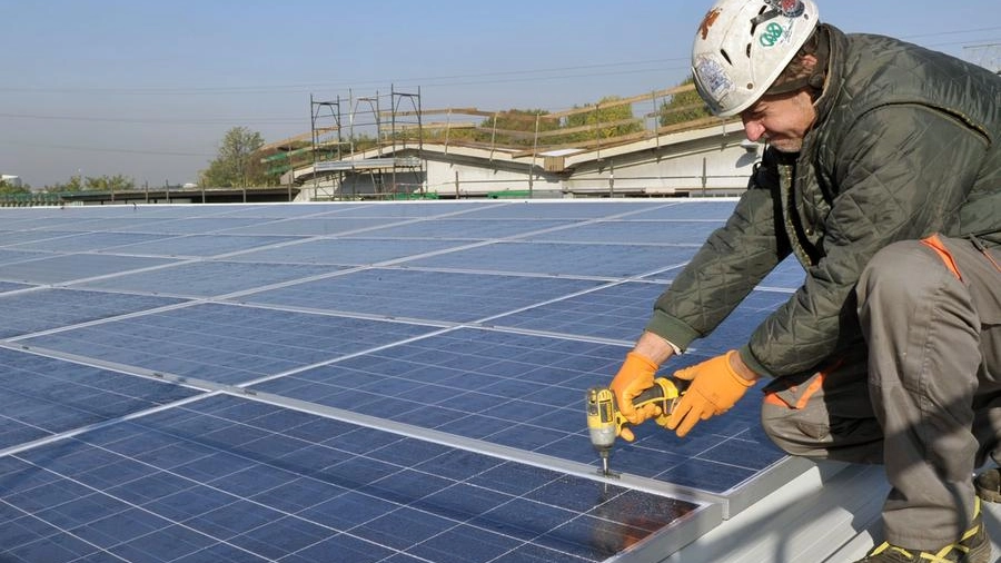 Un operaio lavora su alcuni pannelli solari su un tetto (Foto archivio)