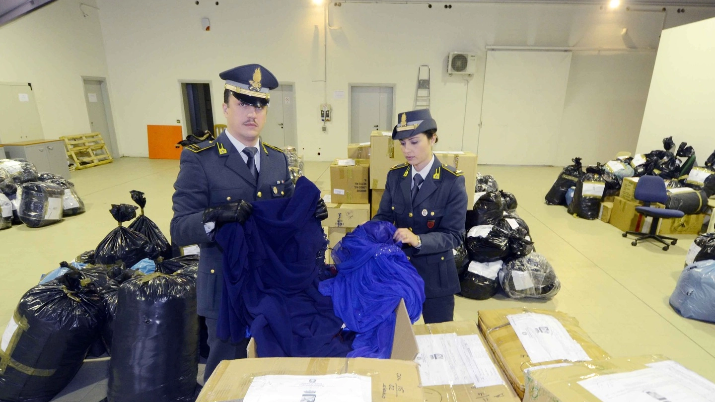 Gli agenti della Guardia di Finanza mostrano  i sacchi di abbigliamento sequestrato