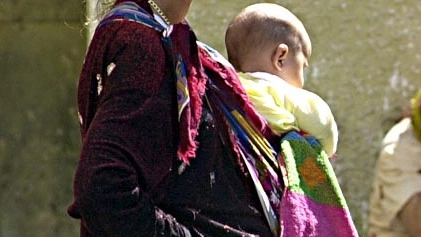Una donna con un bimbo nella fascia porta bebè (Novi)