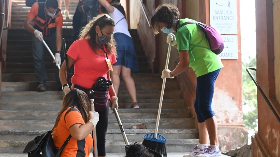 Alcuni volontari ripuliscono il portico di San Luca, in via di ristrutturazione da tempo