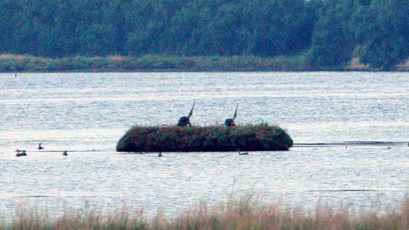 Due cacciatori nascosti in uno dei tradizionali ‘capanni’ di canne, nelle lagune del Delta
