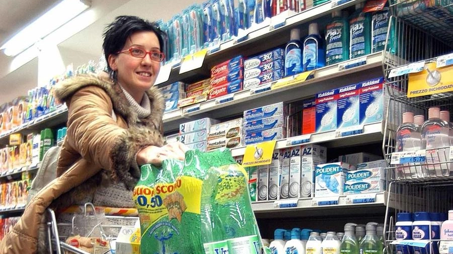 Una donna in una corsia di un supermercato con il carrello colmo della spesa