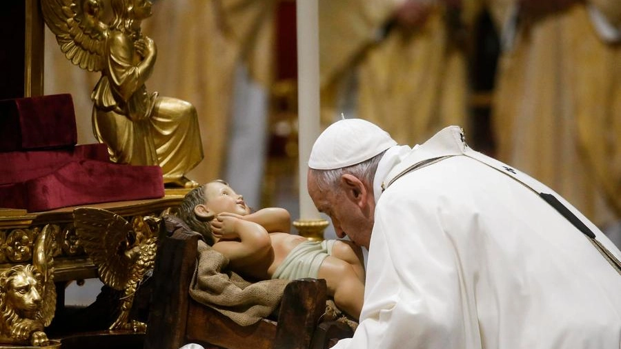 Papa Francesco bacia Gesù bambino durante la messa di Natale in San Pietro (Ansa)