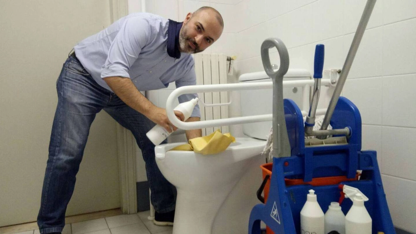 Massimo Bugani mentre pulisce uno dei bagni di Palazzo d’Accursio