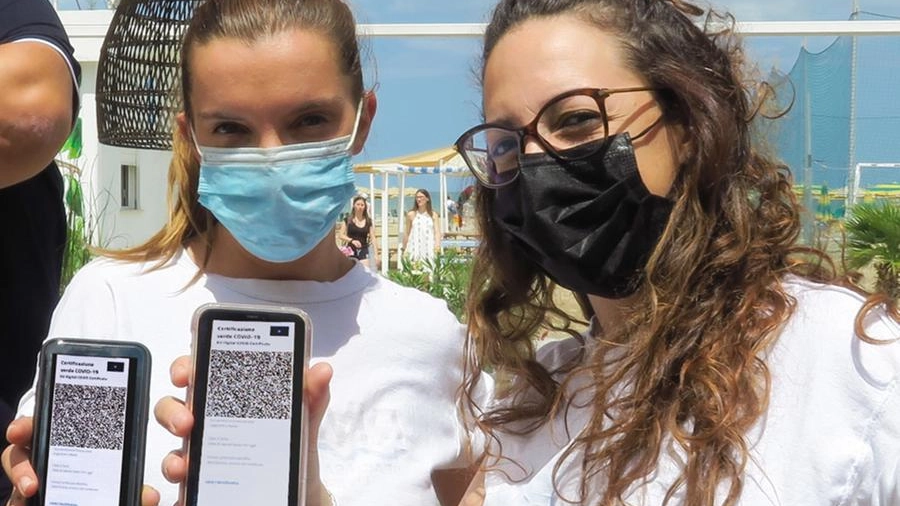 Due ragazze mostrano la certificazione dell’avvenuta vaccinazione o guarigione