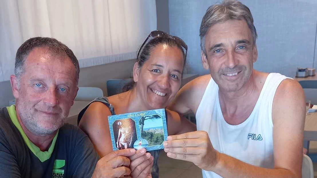 Massimiliano Biancucci consegna la cartolina alla coppia in vacanza