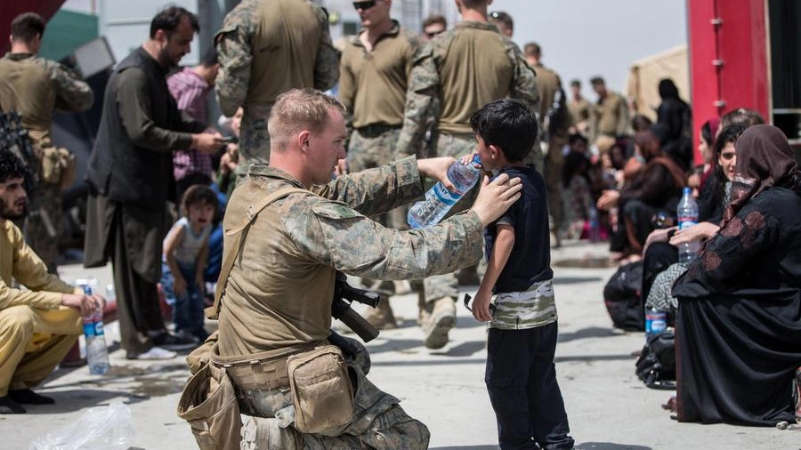 Un marines fa bere un bambino all'aeroporto di Kabul (Ansa)