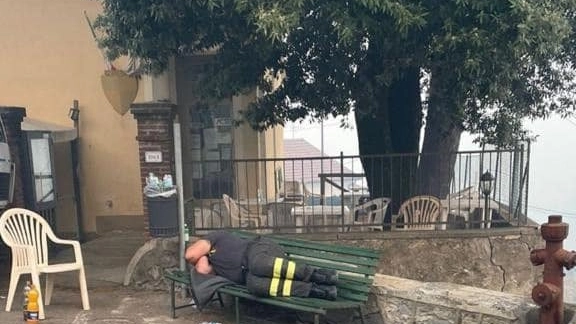 Il vigile del fuoco stremato su una panchina  a Gualdo, Massarosa (Lucca) 