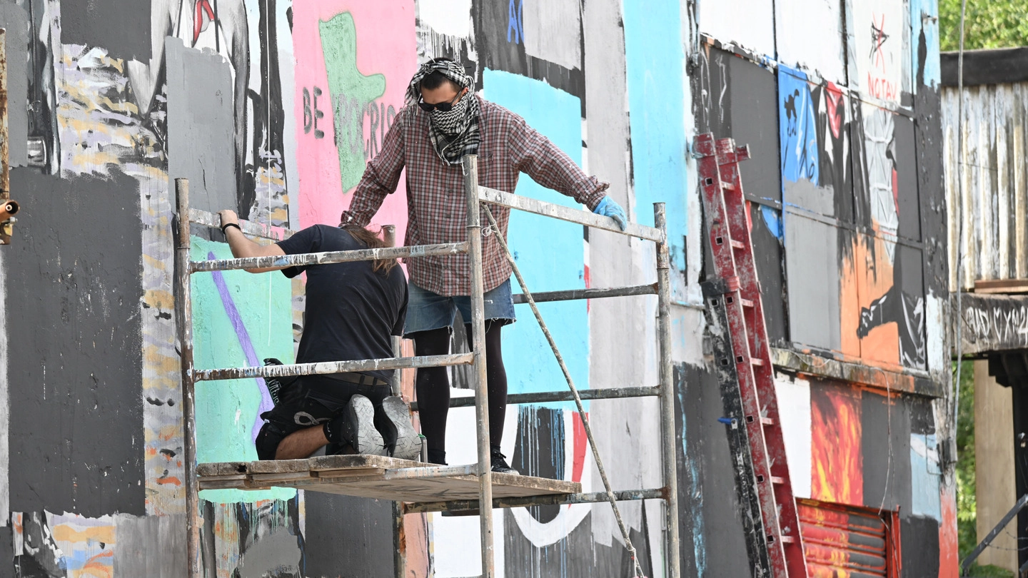 Gli attivisti del centro sociale Xm24 di via Fioravanti all’opera per cancellare i murales
