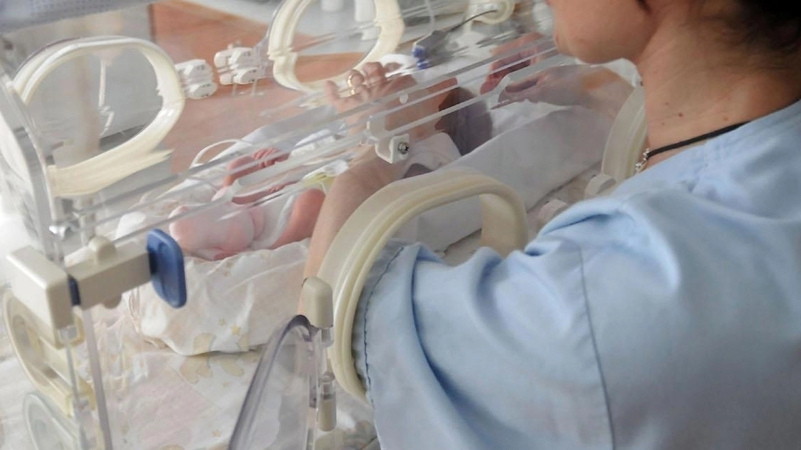 Una infermiera guarda un neonato in ospedale