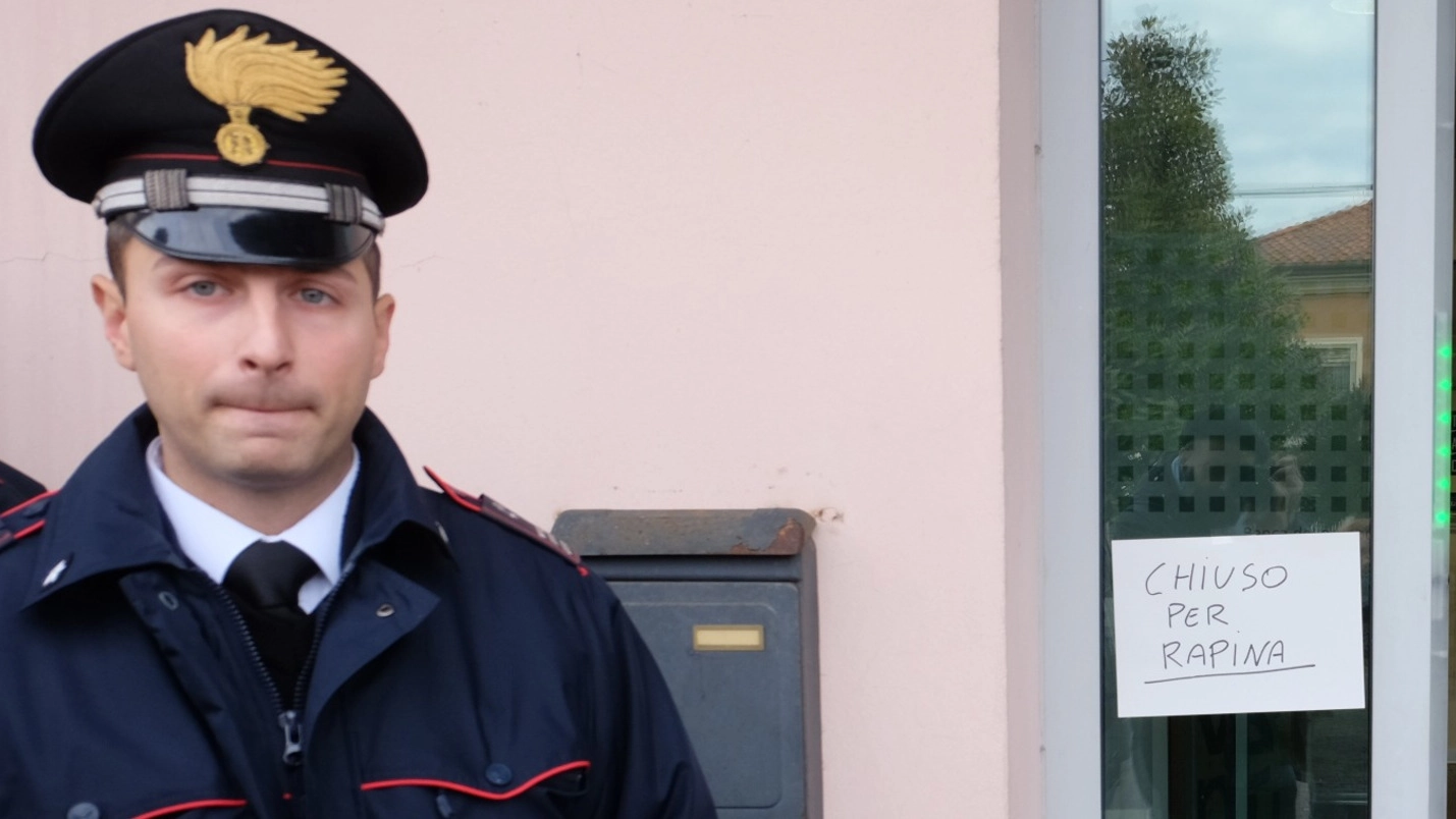 Un carabiniere di fianco al cartello ‘chiuso per rapina’