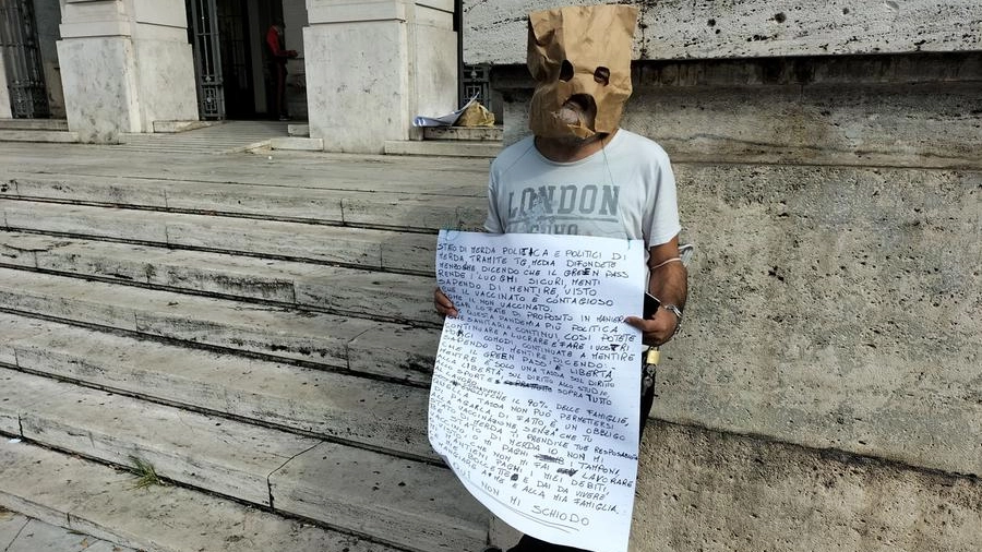 L'uomo col volto coperto per garantire l'anonimato protesta davanti il Comune