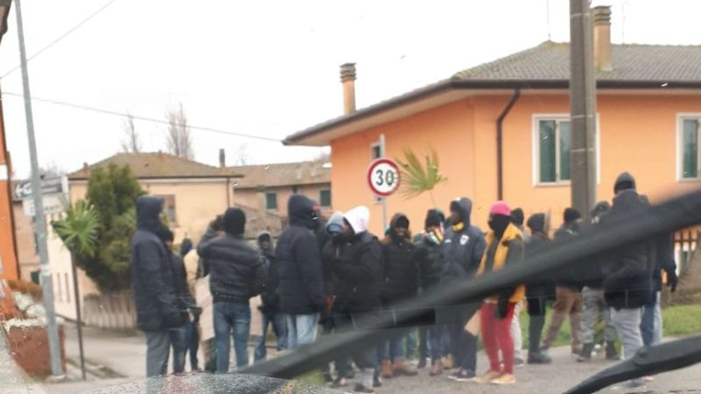 I migranti mentre protestano al freddo e sotto la pioggia davanti al centro d’accoglienza