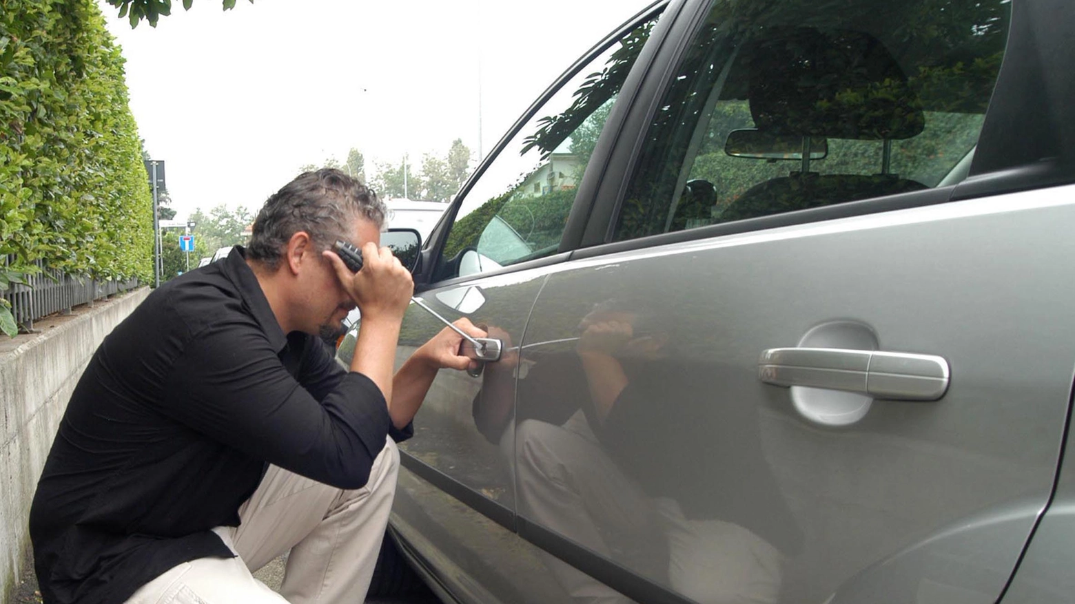 Furti sulle auto: un ladro scassina la serratura di una macchina, foto geenerica