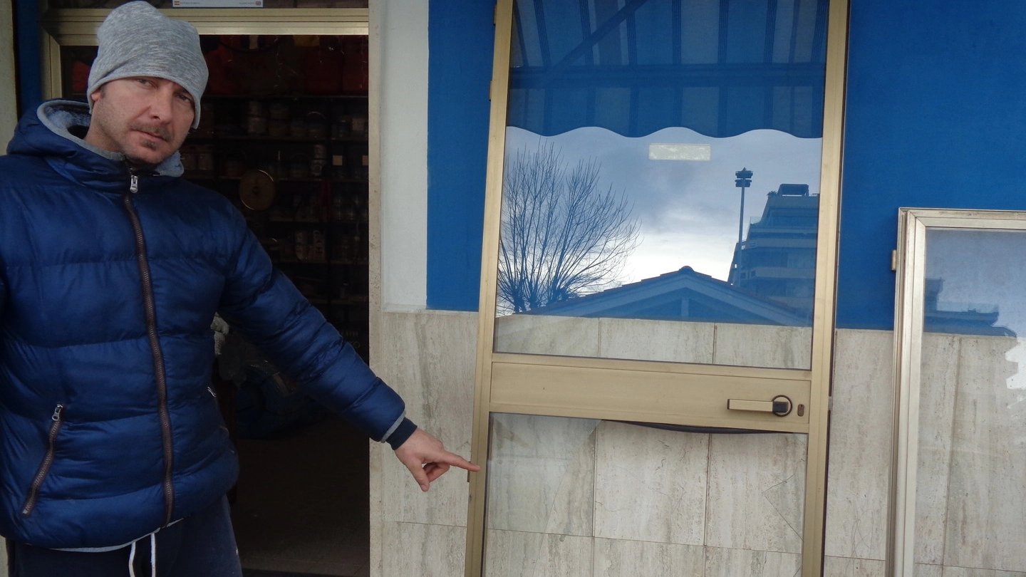 Giovanni Paci mostra il vetro infranto del negozio Retimar