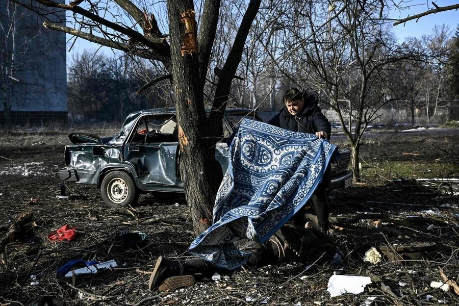 Un uomo copre un cadavere dopo il bombardamento della città di Chuguiv