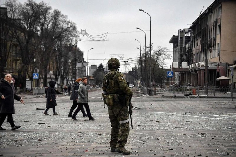 Civili ucraini passano vicino a un soldato russo nella città di Mariupol (Ansa)