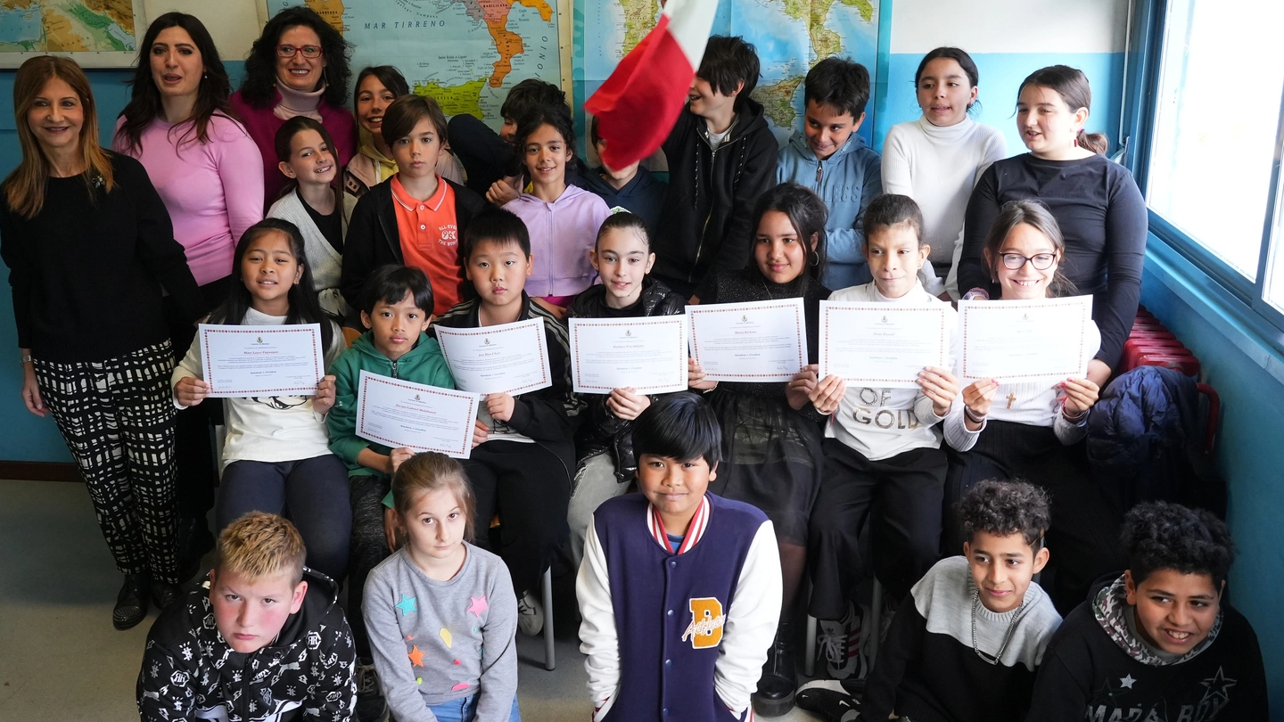 I bambini stranieri con le maestre mostrano il certificato di cittadinanza onoraria