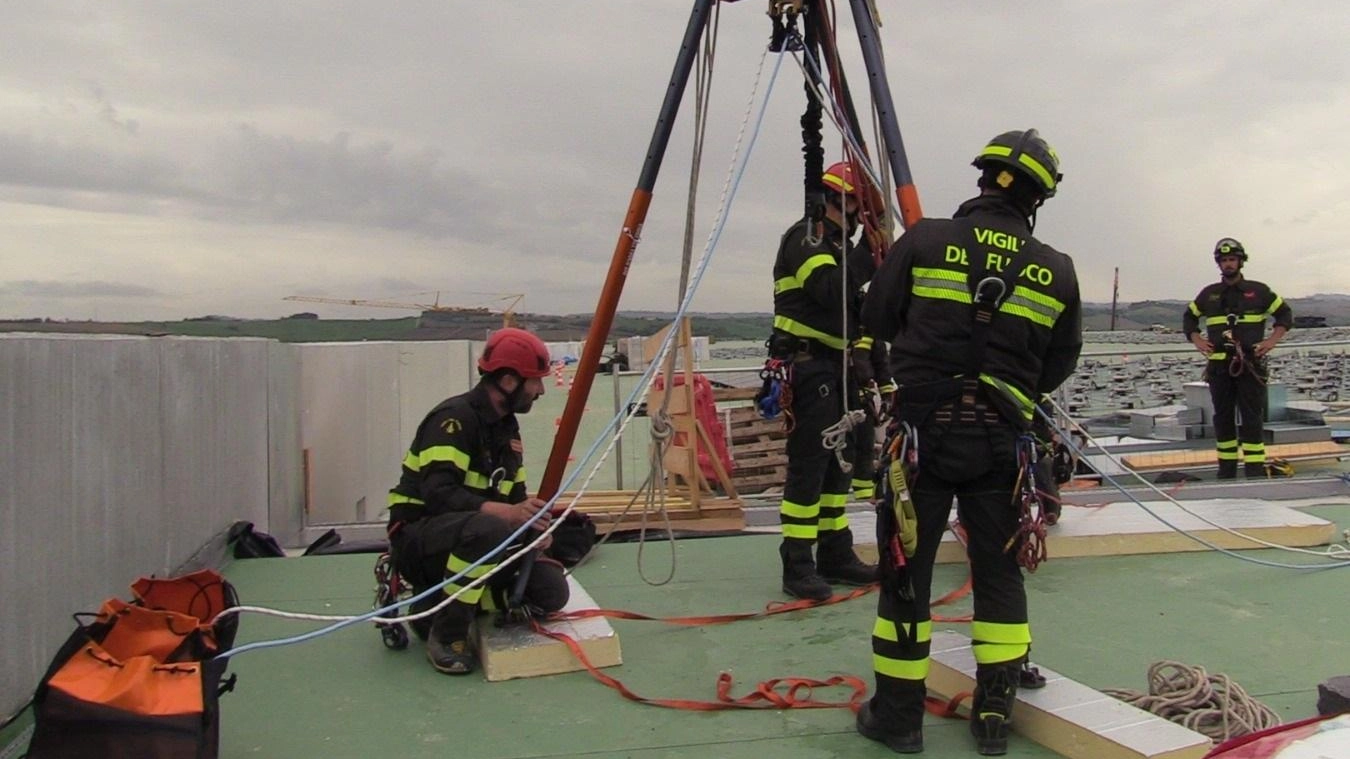 Esercitazione dei vigili del fuoco ad Ancona nel capannone Amazon a Jesi per soccorrere un uomo ferito sul tetto con tecniche innovative e attrezzature speciali.
