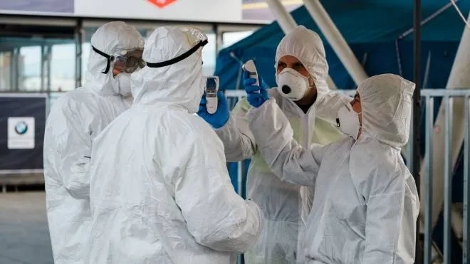 Security members wearing protective gear get ready to check body temperature to people who have to embark in the port of Naples, southern Italy, on March 10, 2020. Today a new government decree has entered into force to extend restrictions to combat coronavirus to the whole national territory, so people cannot move except for work reasons, shopping for food or for medical needs.