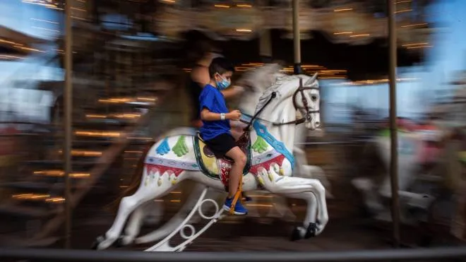 epaselect epa08580871 A boy wearing mask enjoy in a carousel at Tibidabo Amusement Park, during his reopening in Barcelona, Catalonia, Spain, 02 August 2020. Tibidabo Amusement Park reopened his doors under strict measures due to the ongoing pandemic of the coronavirus SARS-CoV-2, which causes the Covid-19 disease.  EPA/Enric Fontcuberta