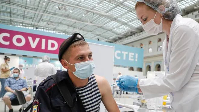 epa09346339 A Russian policeman receives a shot of Russia's Sputnik V vaccine against COVID-19 disease at a vaccination center in Gostinny Dvor, a huge exhibition place in Moscow, Russia, 15 July 2021. More than 500,000 Muscovites received the first component of the coronavirus vaccine in a week. Moscow being the epicentre of the new outbreak of the infections by the new Delta variant. Moscow authorities imposed a ban to serve people without QR-codes confirming vaccination against Covid-19 at public waterings, including people recovering from coronavirus Covid-19 disease within six months before the visit, or negative PCR test taken no earlier than 72 hours before the visit. More than 5,000 cases of COVID-19 were detected in Moscow, 32 per cent more than the day before.  EPA/MAXIM SHIPENKOV